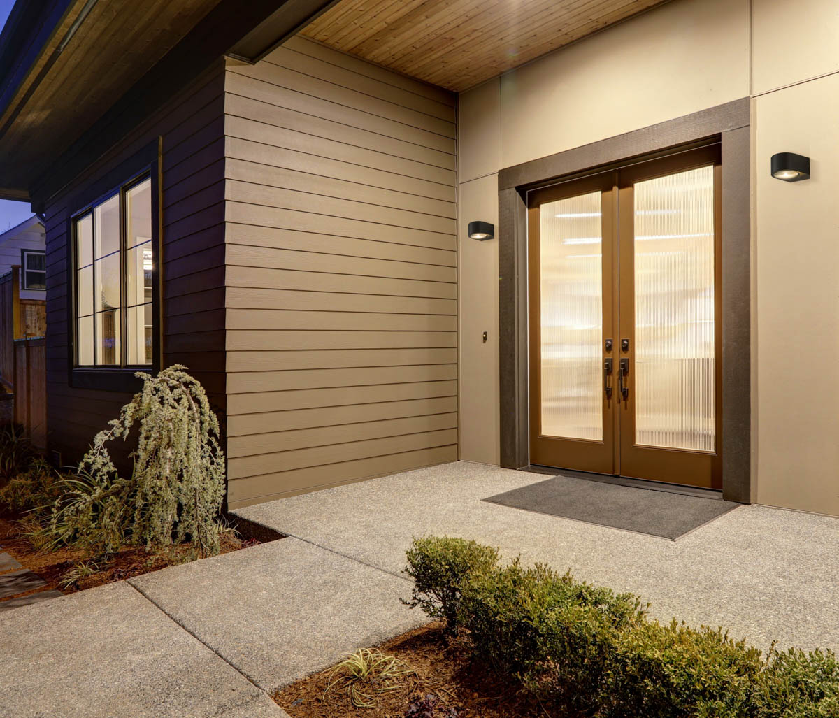 New construction home with low slope roof and brown siding. OWL 8081 3K aranz